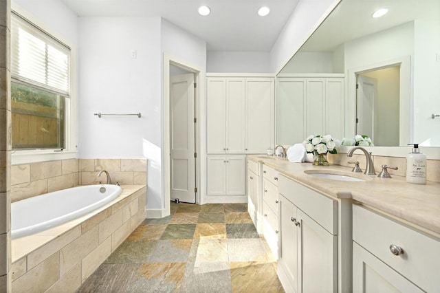 bathroom featuring tiled tub and vanity