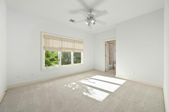 unfurnished bedroom with ceiling fan, light colored carpet, and connected bathroom