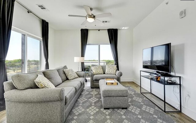 living room featuring ceiling fan, wood-type flooring, and a wealth of natural light