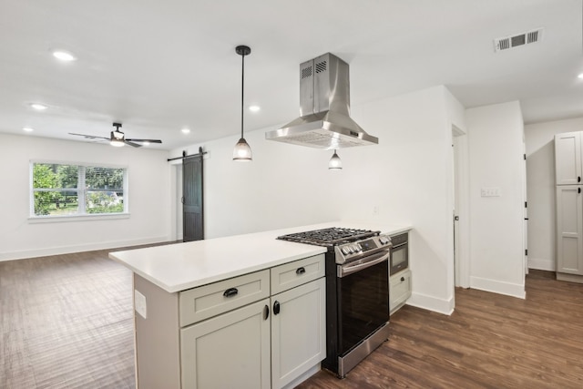 kitchen with stainless steel range, dark wood-type flooring, a barn door, ceiling fan, and island exhaust hood