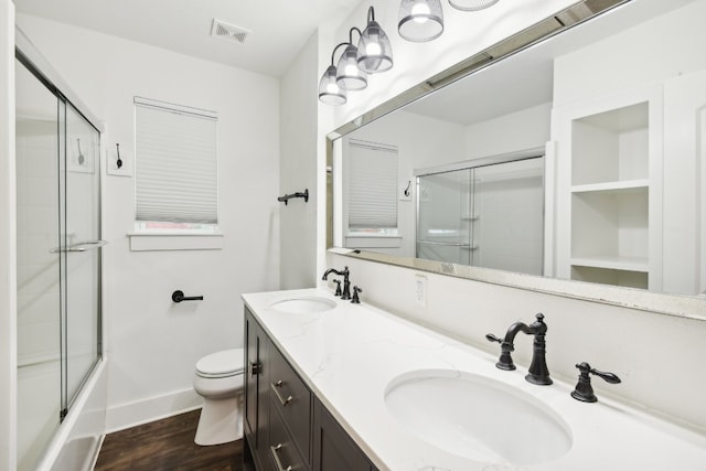 full bathroom with enclosed tub / shower combo, wood-type flooring, toilet, and double sink vanity