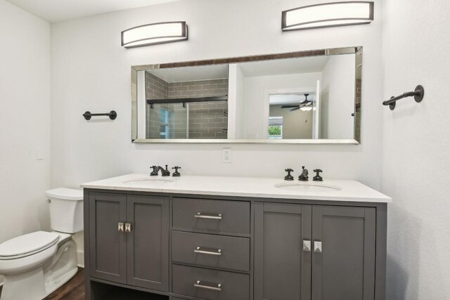 bathroom with double vanity, hardwood / wood-style floors, toilet, and ceiling fan