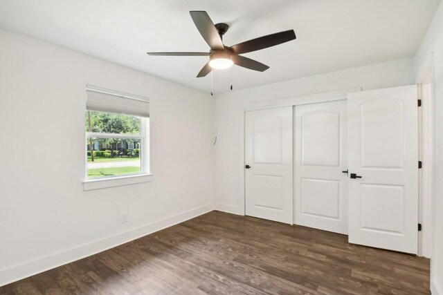 unfurnished bedroom with dark hardwood / wood-style floors, ceiling fan, and a closet