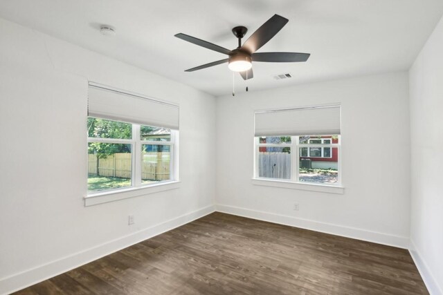 empty room featuring plenty of natural light, dark wood-type flooring, and ceiling fan