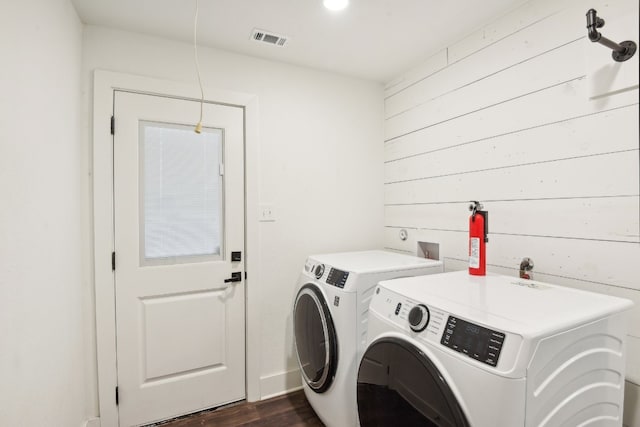 laundry room with wood walls, dark hardwood / wood-style floors, and independent washer and dryer