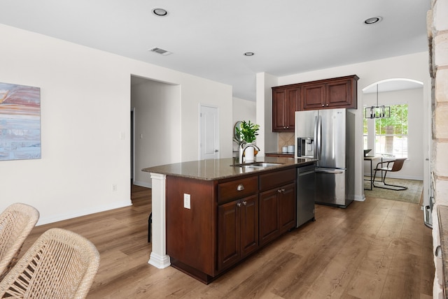 kitchen featuring dark brown cabinetry, sink, a center island with sink, appliances with stainless steel finishes, and dark hardwood / wood-style flooring