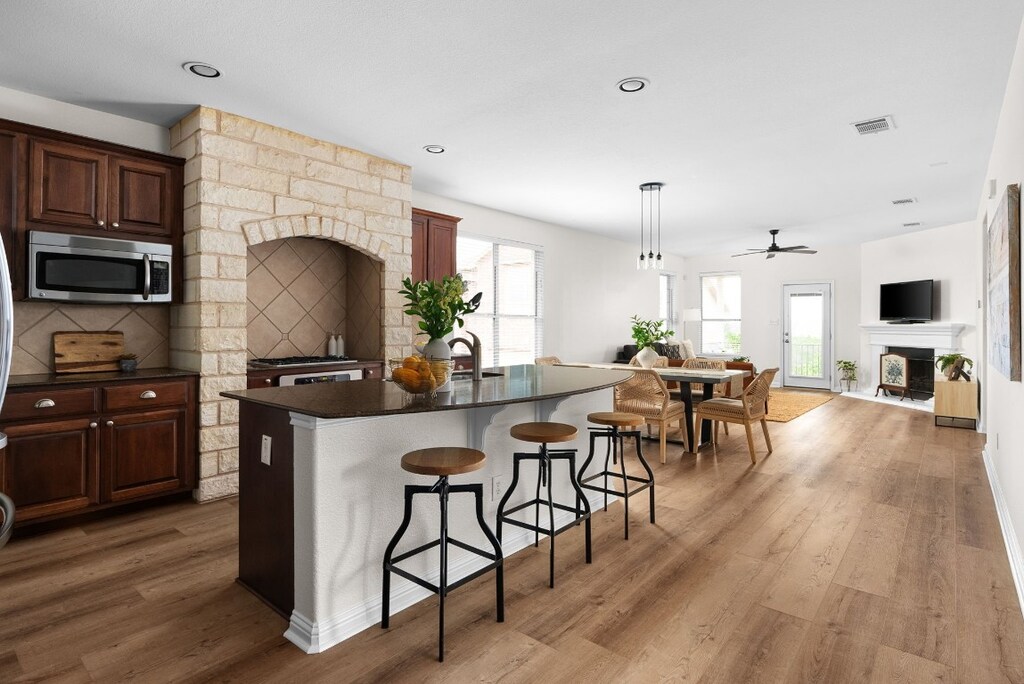 kitchen featuring plenty of natural light, a breakfast bar area, an island with sink, and hardwood / wood-style floors