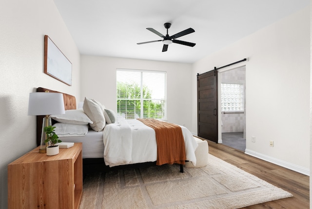 bedroom featuring ceiling fan, a barn door, and hardwood / wood-style floors