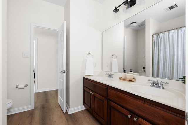 bathroom with vanity, toilet, and hardwood / wood-style floors