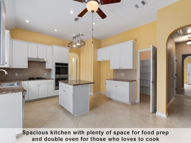 kitchen with decorative backsplash, a center island, light tile patterned floors, and white cabinets