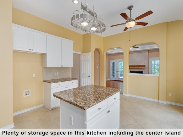 kitchen featuring white cabinetry, backsplash, a brick fireplace, and a kitchen island