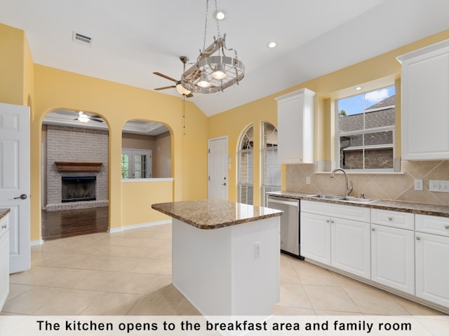 kitchen with white cabinetry, ceiling fan, decorative backsplash, sink, and a brick fireplace