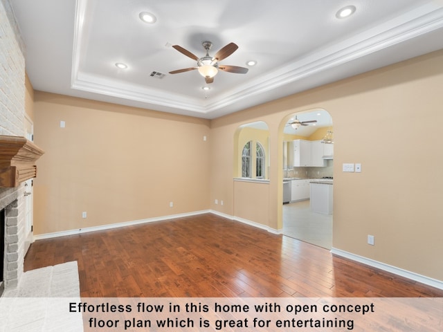 unfurnished living room featuring a tray ceiling, a fireplace, ceiling fan, and tile patterned floors