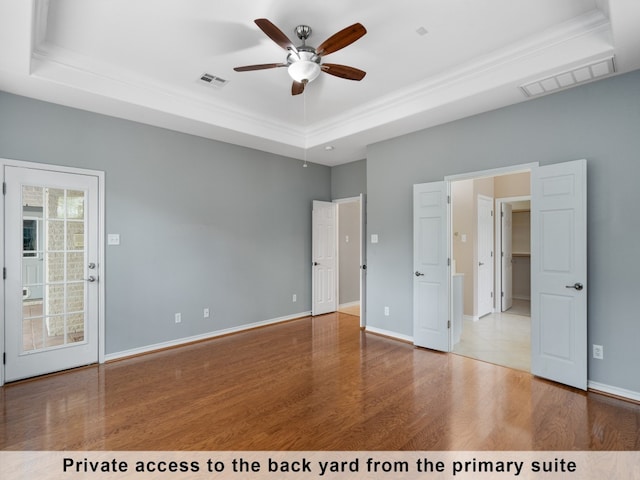 unfurnished bedroom with ceiling fan, wood-type flooring, and a raised ceiling