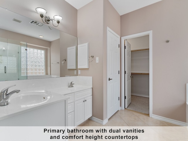 bathroom with tile patterned flooring, a shower with door, and dual bowl vanity