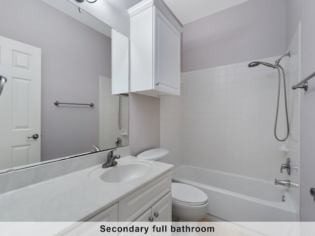 full bathroom featuring vanity, tiled shower / bath combo, and toilet