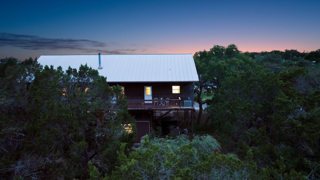 back house at dusk with a deck and central AC unit