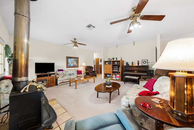 living room with light carpet, ceiling fan, and a wood stove