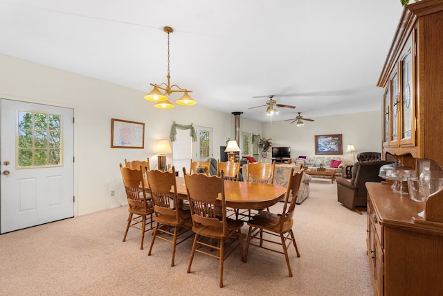 dining area with ceiling fan with notable chandelier and light colored carpet