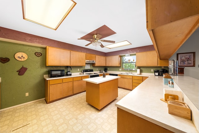 kitchen featuring a skylight, sink, white gas stove, kitchen peninsula, and a center island with sink