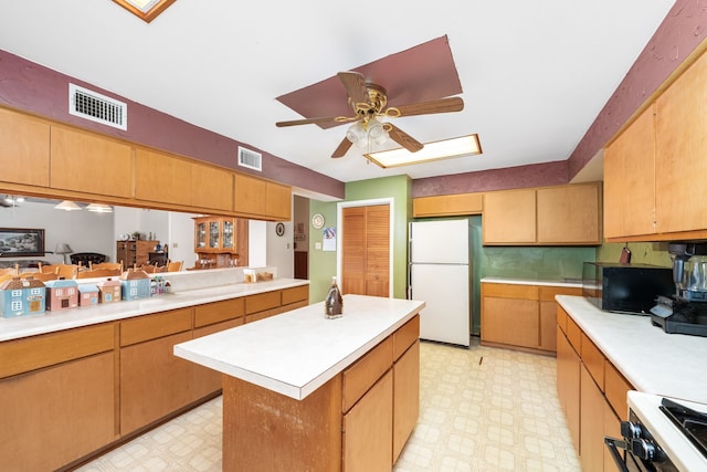 kitchen with ceiling fan, a center island, white fridge, and range