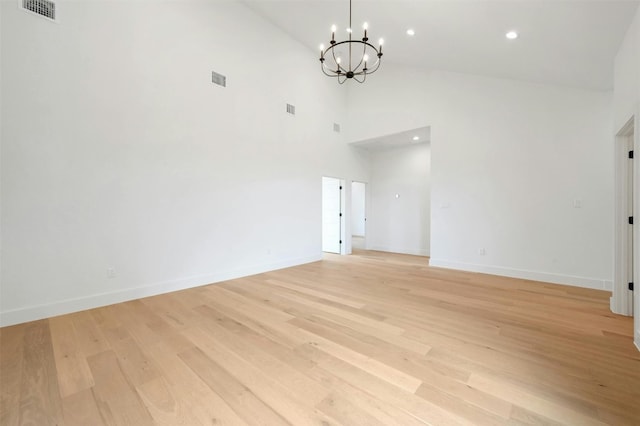 spare room featuring high vaulted ceiling, a chandelier, and light hardwood / wood-style flooring