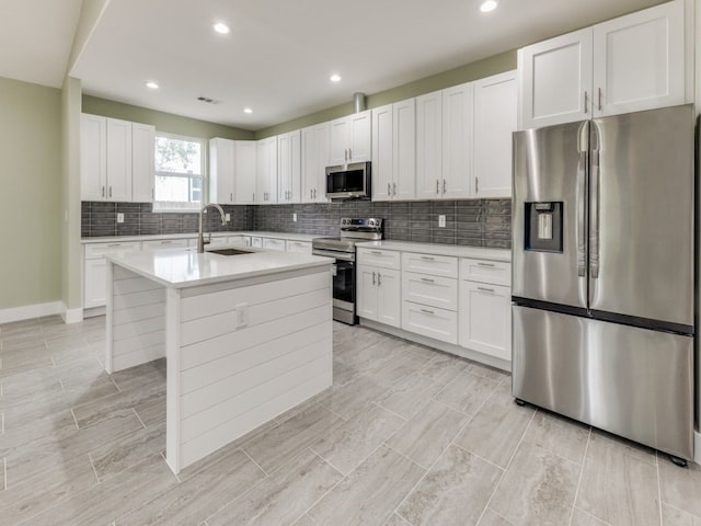 kitchen featuring sink, stainless steel appliances, white cabinets, and a center island with sink