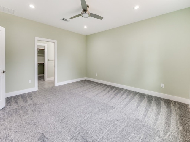 interior space with light carpet, a closet, ceiling fan, and a walk in closet