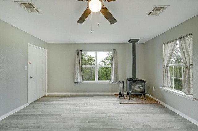 interior space featuring ceiling fan, a wood stove, and light hardwood / wood-style flooring