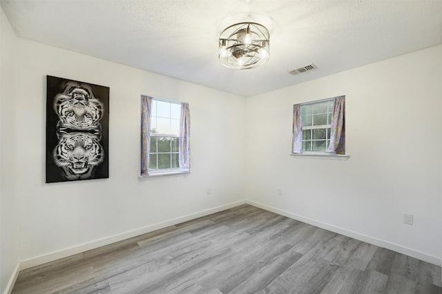 empty room with a textured ceiling and light wood-type flooring