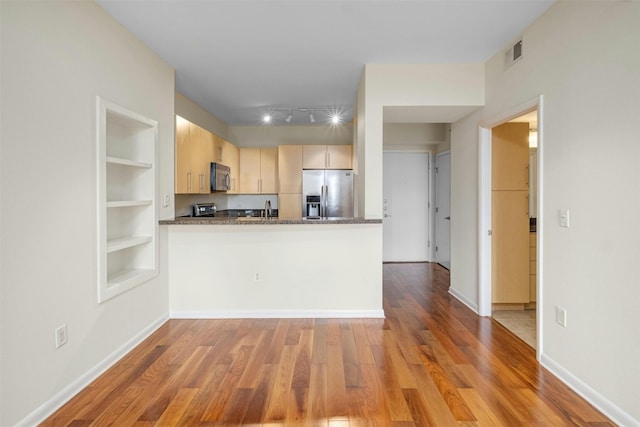 kitchen featuring light hardwood / wood-style flooring, built in features, stainless steel appliances, kitchen peninsula, and light brown cabinets