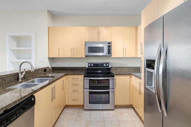 kitchen with appliances with stainless steel finishes, light brown cabinetry, sink, and dark stone countertops