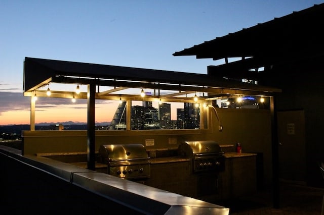 patio terrace at dusk with an outdoor kitchen and area for grilling