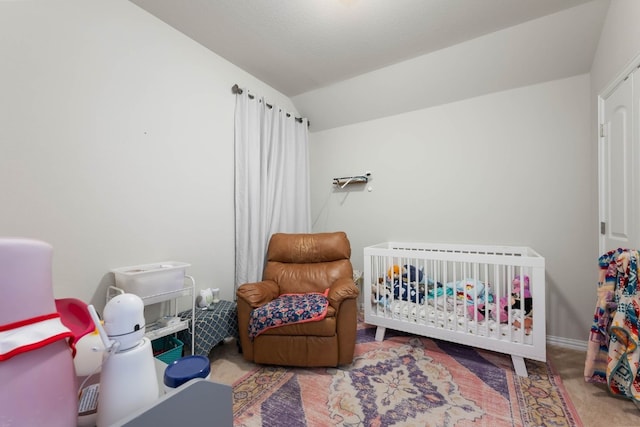 bedroom with a crib, lofted ceiling, and carpet