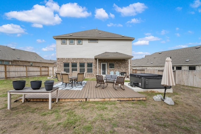 back of house featuring a deck, a lawn, and a hot tub