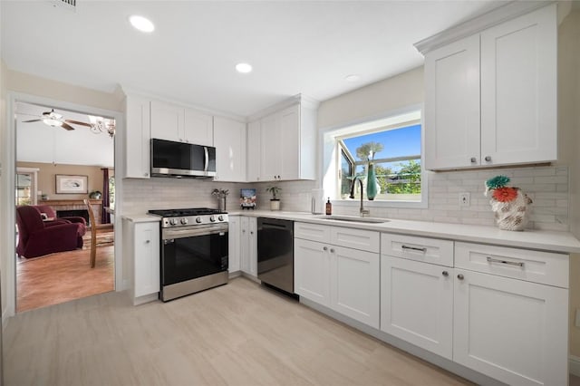 kitchen featuring sink, ceiling fan, appliances with stainless steel finishes, white cabinetry, and tasteful backsplash