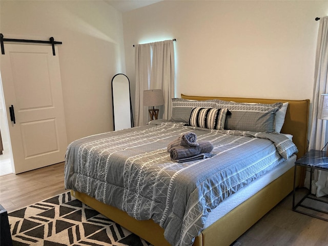 bedroom with a barn door and light hardwood / wood-style floors