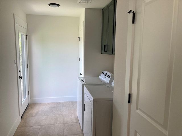 laundry area featuring washing machine and clothes dryer, light tile patterned floors, and cabinets