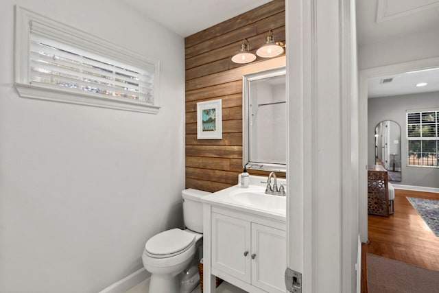 bathroom featuring vanity, wood walls, toilet, and wood-type flooring