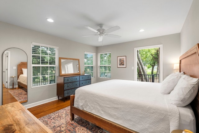 bedroom featuring access to outside, hardwood / wood-style flooring, multiple windows, and ceiling fan