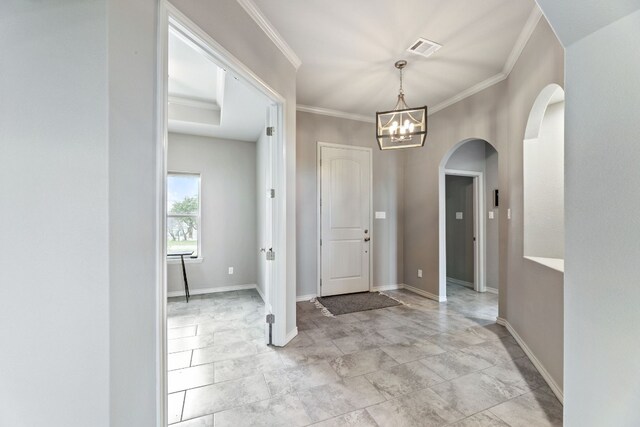 tiled entryway featuring a notable chandelier and crown molding