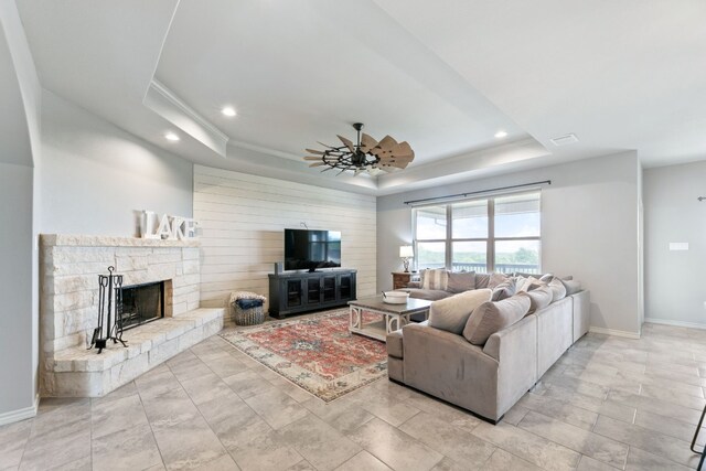 living room featuring a fireplace, light tile patterned floors, and a tray ceiling