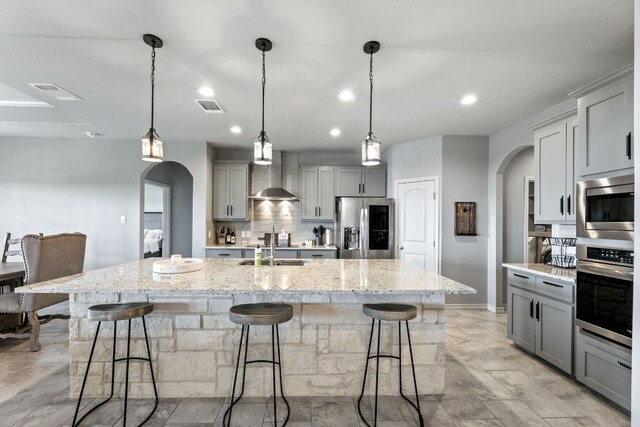 kitchen with a center island with sink, appliances with stainless steel finishes, and a kitchen bar