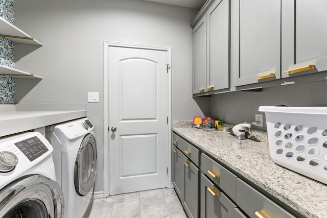 laundry area with washing machine and dryer, cabinets, and light tile patterned floors