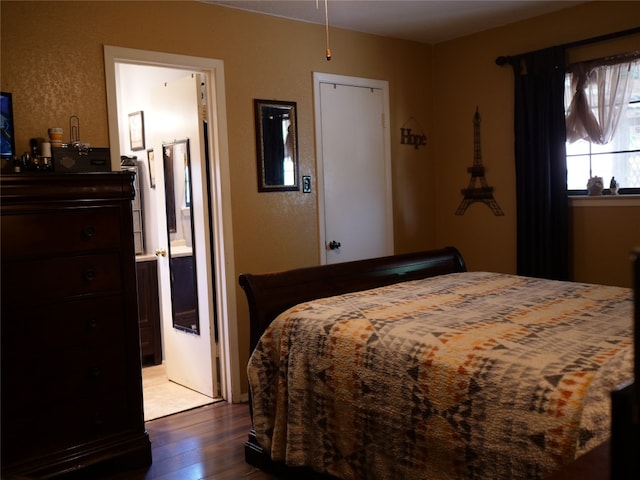 bedroom featuring connected bathroom and dark hardwood / wood-style flooring