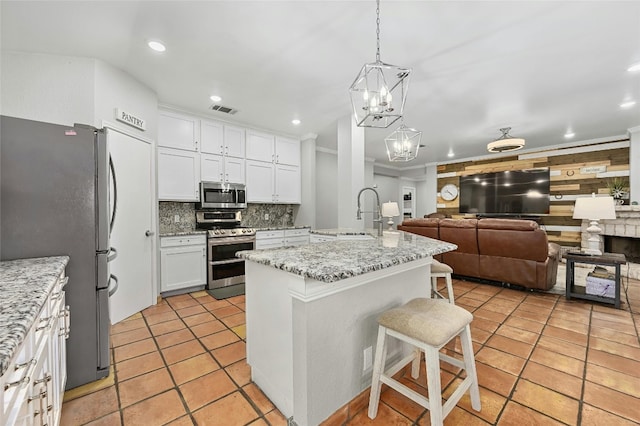 kitchen with visible vents, white cabinets, a breakfast bar area, open floor plan, and stainless steel appliances