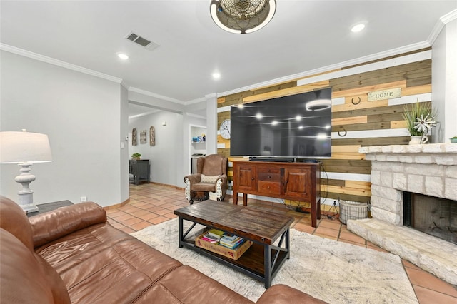 living area featuring light tile patterned floors, visible vents, ornamental molding, a stone fireplace, and recessed lighting