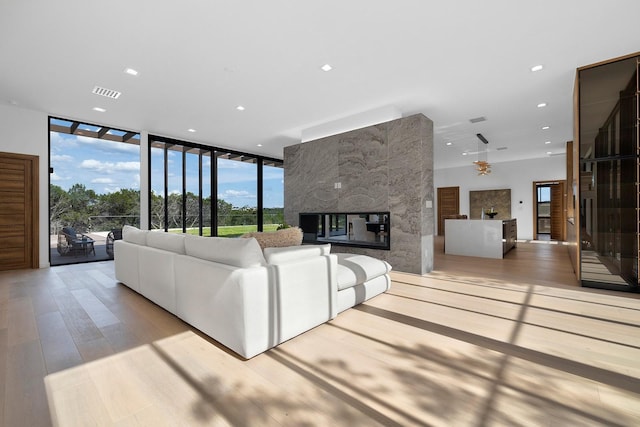 unfurnished living room with a notable chandelier, floor to ceiling windows, a fireplace, and light wood-type flooring