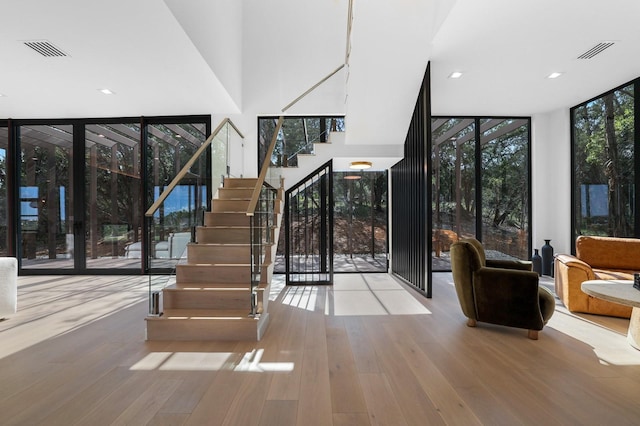 stairway with expansive windows, visible vents, and wood finished floors