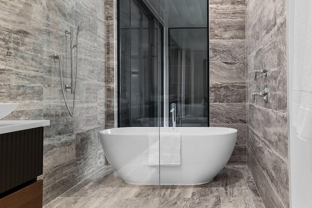 bathroom with tile walls, a freestanding tub, tiled shower, and vanity